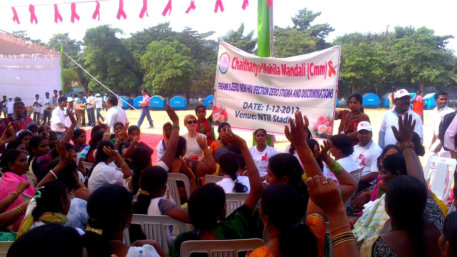 Women raising their hands at a Chaithanya Mahila Mandali World AIDS Day rally under strings of red ribbons, NTR Stadium, Hyderabad, 2012