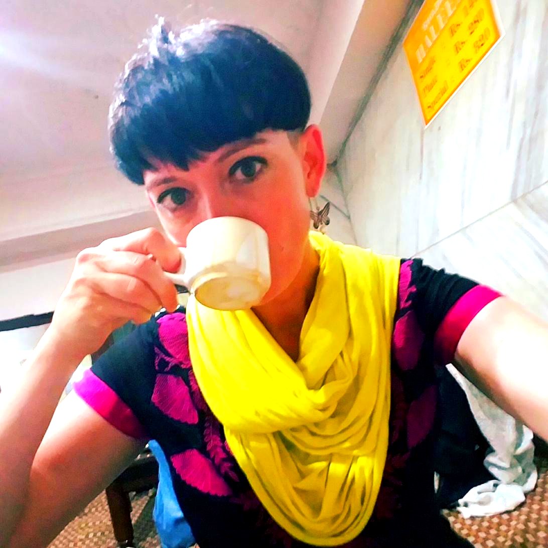 Kimberly Walters drinking chai near Charminar, Hyderabad, wearing a yellow scarf